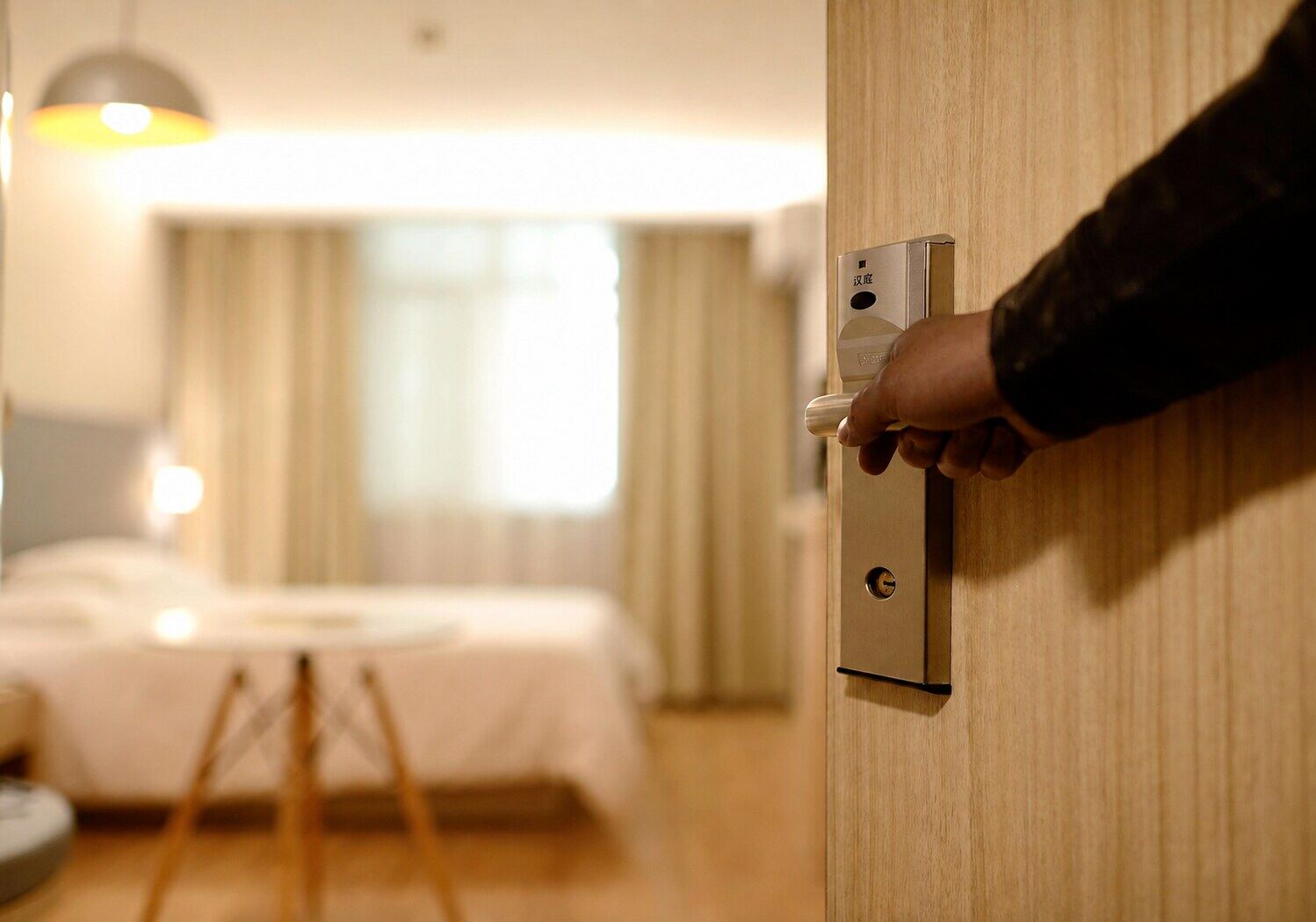 A guest opening the door to a well-prepared hotel room